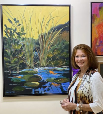 Linda Mack standing next to her painting "Yellow Sky"